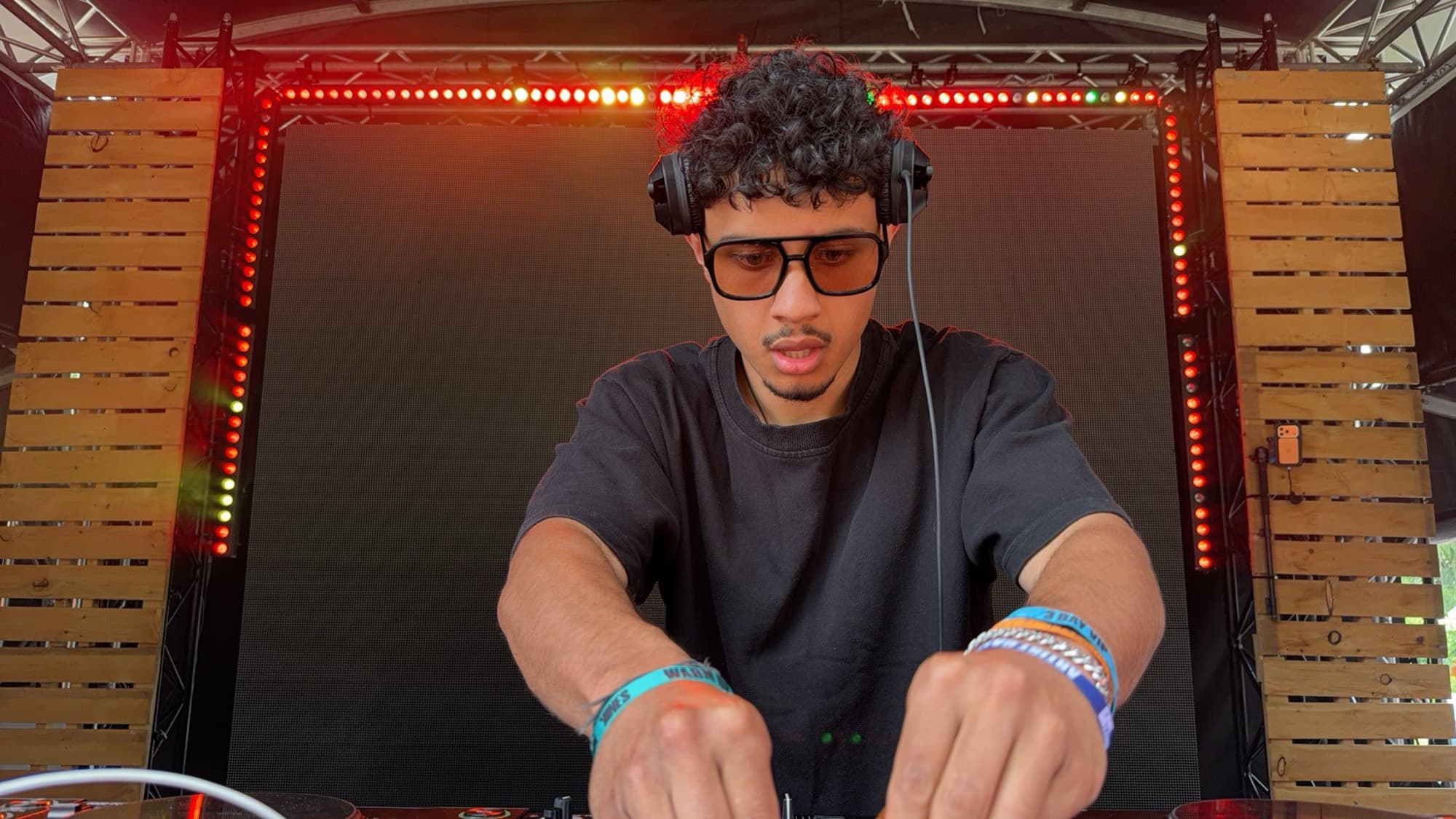Close-up of a DJ in headphones reaching for the mixer