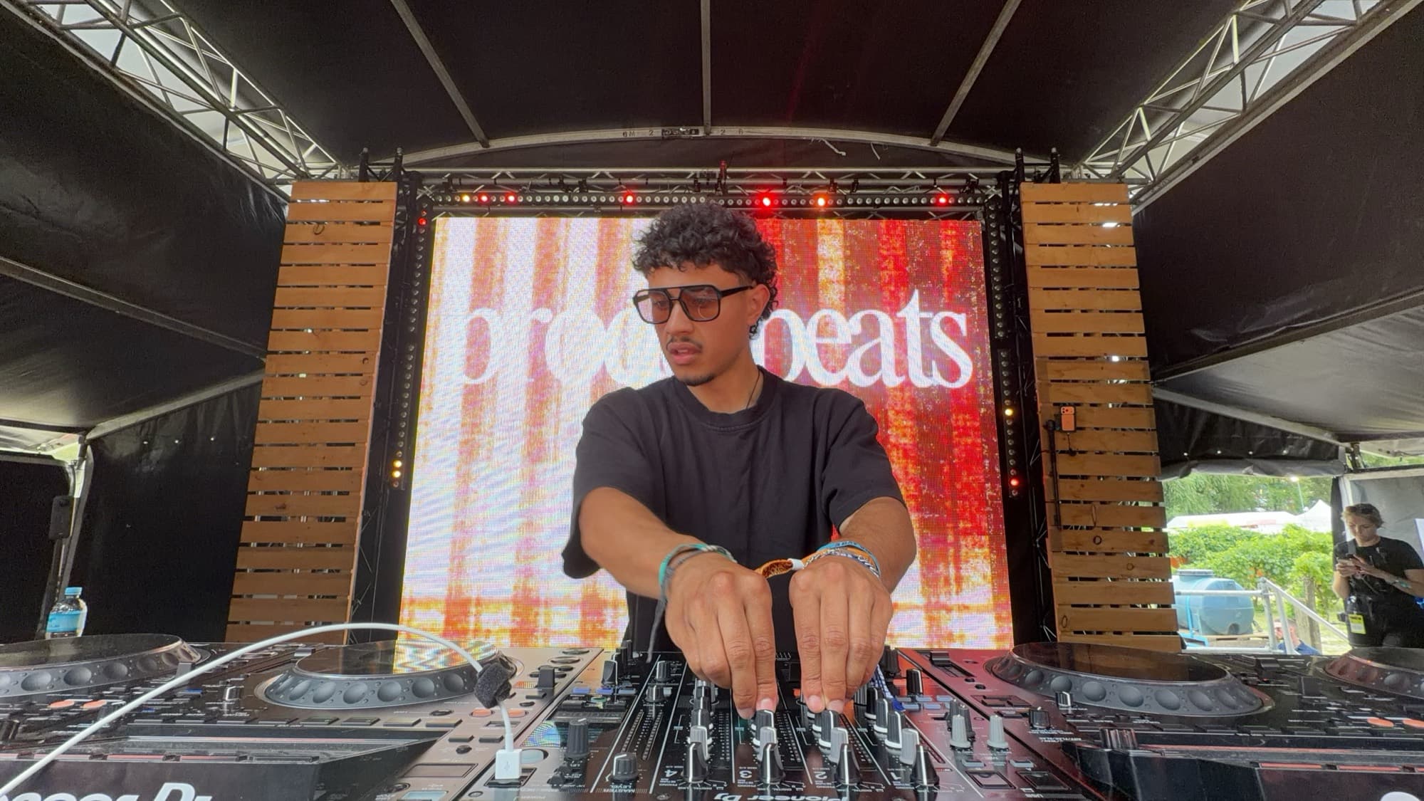 A DJ adjusting the mixer on an outdoor festival stage